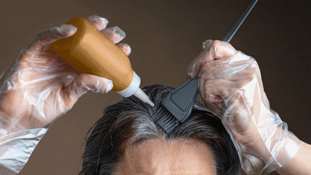 Woman applying hair dye to grey roots